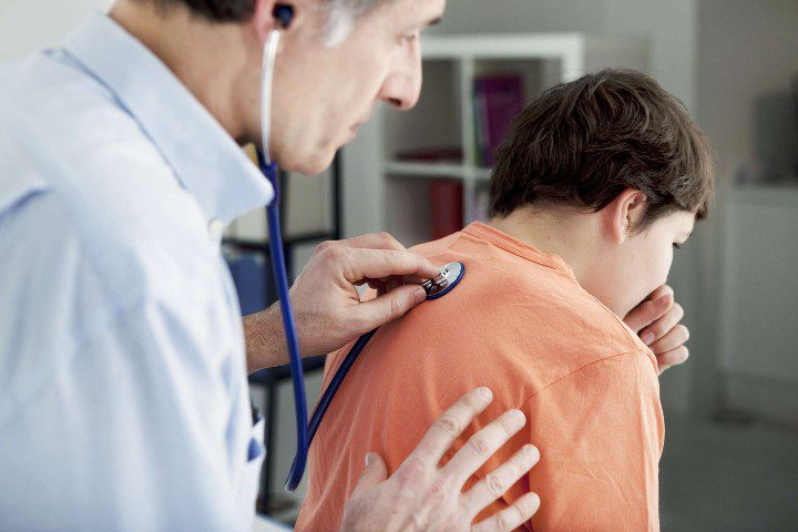 Доктор осматривает пациента мальчика с кашлем